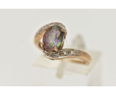 A 9CT GOLD MYSTIC TOPAZ AND DIAMOND RING, centring on an oval cut mystic topaz, four claw set, within cross over shoulders se