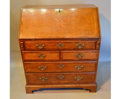 A George II Oak Bureau, the fall front with star inlay enclosing a fitted interior above five drawers with brass handles and 
