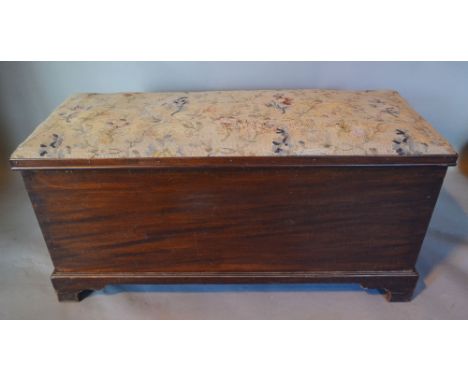 A Late 19th Early 20th Century Mahogany Chest, the tapestry upholstered hinged top above a plain front raised upon bracket fe
