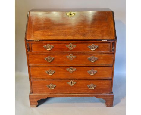 A George III Mahogany Bureau, the fall front enclosing a fitted interior above four long drawers with brass handles and escut