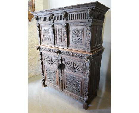 A 19th Century Oak Court Cupboard, the moulded cornice above three carved panel doors with carved lion mask mounts, the lower