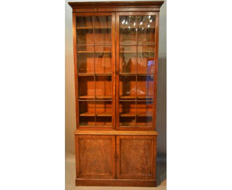 An Early 19th Century Mahogany Library Bookcase, the moulded cornice above two astragal glazed doors enclosing shelves above 