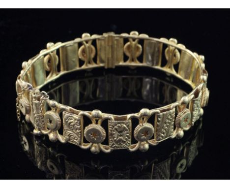 An early 20th century Indian 22ct gold hinged bangle, of openwork design, with engraved rectangular panels and roundels with 