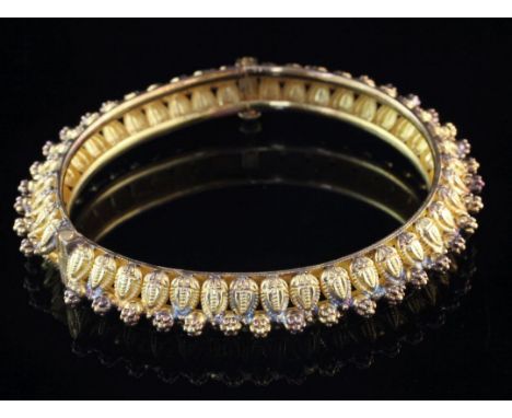 A Middle Eastern Etruscan style 22ct gold hinged bangle, with raised stylised leaves and flower head decoration, gross 38 gra