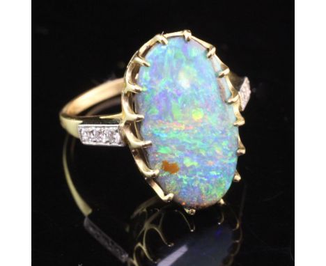 An 18ct gold and white opal ring with round brilliant cut diamond set shoulders, the oval opal weighing approximately 9.00ct,