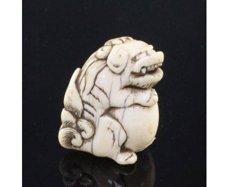 A Japanese ivory netsuke of a shi-shi, Edo period, seated and holding a ball, 4cm