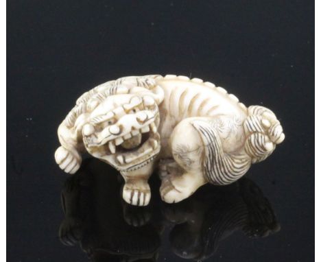 A Japanese ivory netsuke of a shi-shi, signed Ichimin, early Meiji period, with snarling expression and a loose ball in his m