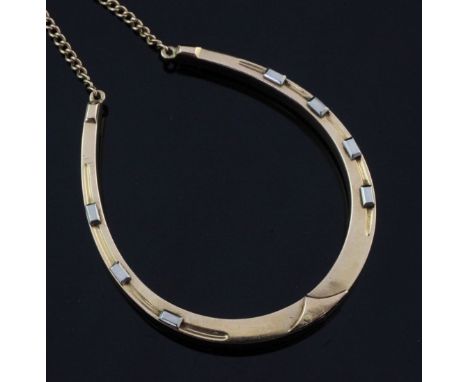 An early 20th century gold and white metal horseshoe shaped hinged bangle, with safety chain, gross 19.8 grams.