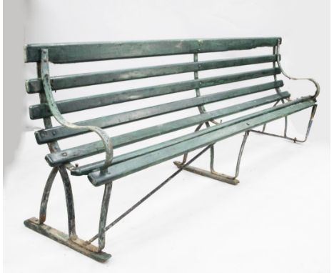 A large green painted railway station bench, with wrought iron sides and wooden slats
