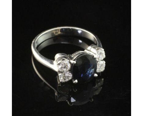 An 18ct white gold, sapphire and diamond ring, with central oval cut sapphire flanked by four round brilliant cut diamonds, s