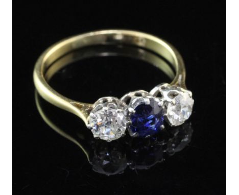 An 18ct gold and three stone sapphire and diamond ring, the central oval cut sapphire flanked by two round cut diamonds, size