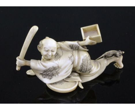 A Japanese ivory okimono of a ratcatcher, Meiji period, the figure crouching and holding a stick and a tray in each hand, the