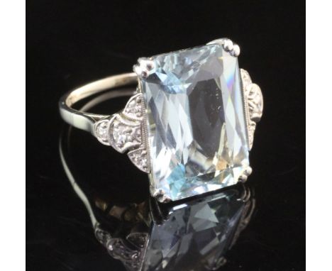 A white gold, aquamarine and diamond set dress ring, the central fancy emerald cut aquamarine weighing 7.71ct, with diamond s