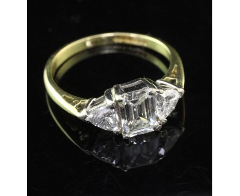 A modern 18ct gold and diamond three stone ring, of elliptical form, with central emerald cut stone weighing approximately 0.