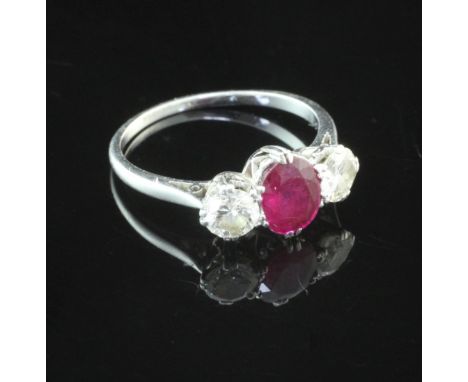 A platinum, ruby and diamond set three stone ring, the central oval cut ruby flanked by two round brilliant cut diamonds, siz