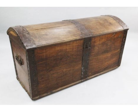 A large 19th century French iron bound oak dome top trunk, the front decorated with two cartouches, one dated 1803, the other