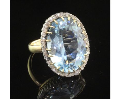 A gold, aquamarine and diamond set dress ring, the large fancy oval cut aquamarine bordered by rose cut diamonds, size I.