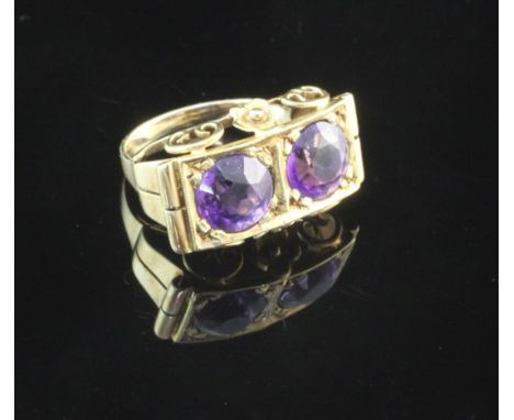 A 14ct gold and amethyst dress ring, of rectangular concave form, with ornate scroll mount and set with two round cut amethys