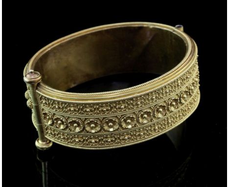 A Victorian gold hinged bangle, with continuous geometric cannetile work decoration and central bands of spheres and flower h