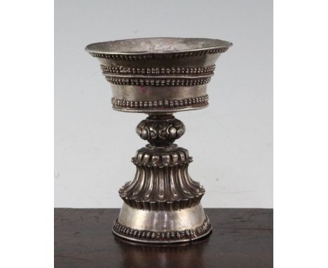 A Tibetan silver yak butter lamp, 19th century, the pan shaped bowl above a baluster stem, with applied beaded decoration, 11