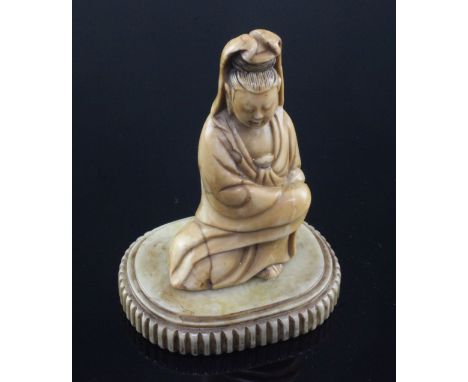 A Chinese soapstone seated figure of Guanyin, 17th / 18th century, the pale russet coloured stone with red veining, on a pale