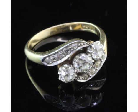 An 18ct gold three stone diamond ring in a diamond twist setting, the three largest stones with a total approximate weight of