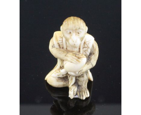 A Japanese ivory netsuke of a seated monkey holding a peach, signed Kogetsu, Meiji period, the monkey wearing a brocade patte