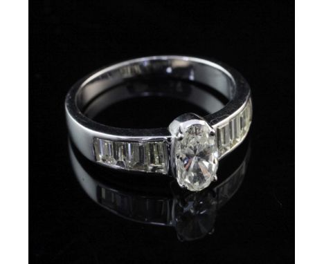 A 14ct white gold and diamond dress ring, set with central oval cut diamond and graduated baguette cut diamond set shoulders,