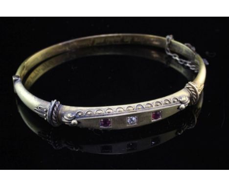 A late Victorian 15ct gold and three stone ruby and diamond set hinged bangle, with cannetile work decoration and interior in