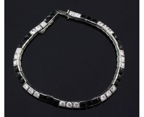 A 1920's/1930's Cartier, platinum, diamond and onyx line bracelet, set with twenty three round cut diamonds and twenty four f
