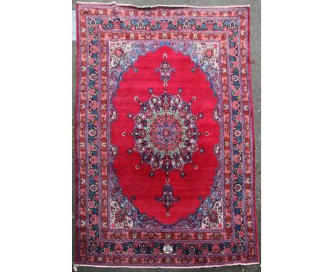 A Persian carpet, with large central medallion on a red ground with foliate angles and three row foliate border, signed, 12ft