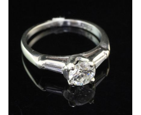 An 18ct white gold and single stone diamond ring with trapeze cut diamond set shoulders, the central round brilliant cut ston