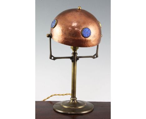 A Jugendstil copper and brass table lamp, with adjustable domed shade, mounted with circular iridescent glass panels, possibl