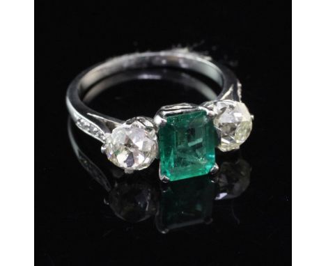 A platinum, emerald and diamond three stone ring, with diamond set shoulders, the emerald weighing approximately 1.21ct and f