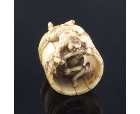 A Japanese ivory netsuke of two men constructing a barrel, Meiji period, one man lying on top of the barrel, the other inside