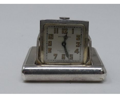 An Art Deco Dunhill silver miniature travel clock, the engine turned case with hinged divided doors enclosing the hinged cloc