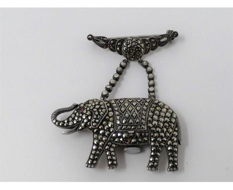 An Art Deco silver, marcasite and ruby novelty elephant brooch watch. Set with round mixed cut marcasite stones and a ruby ca