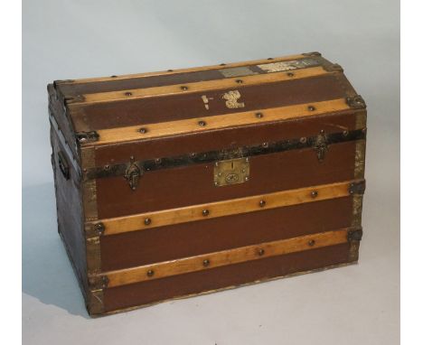 A metal and wooden bound brown fabric covered steamer trunk with domed lid, the front with brass lock plate, papered interior