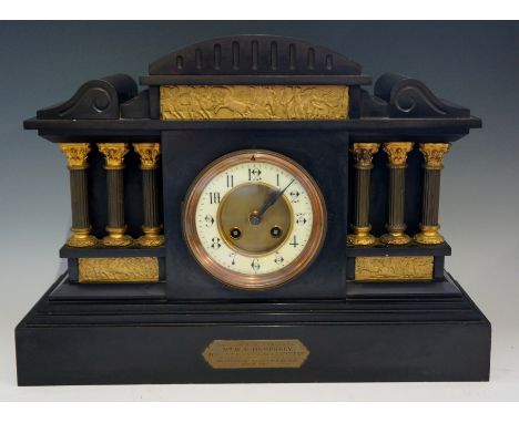 A Victorian black slate mantel clock of architectural form, domed top fluted and flanked by horizontal corbels, the frieze wi