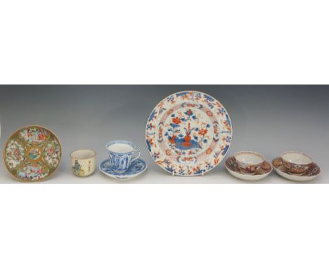 A pair of porcelain tea bowls and shaped circular saucers, each decorated with figures and child in temple landscapes within 