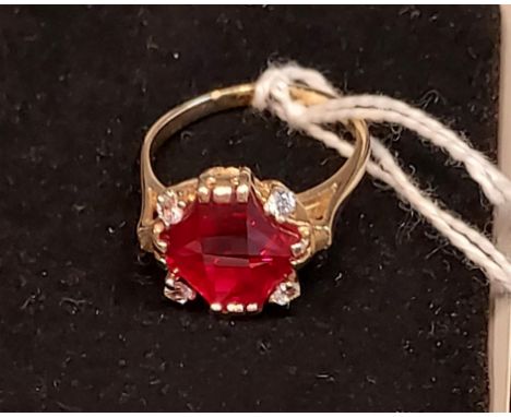 A 14ct yellow gold ring set with a large cut single ruby and four white spinel stones. [Ring size R] [5.87Grams] [Ruby- 6x12x