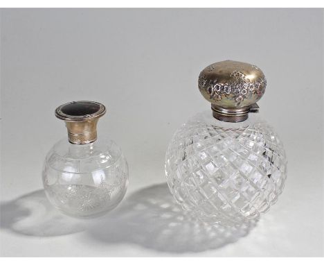 Two silver and glass bottles, the first with a tortoiseshell lid, 9.5cm high, the second embossed with flowers 13cm high