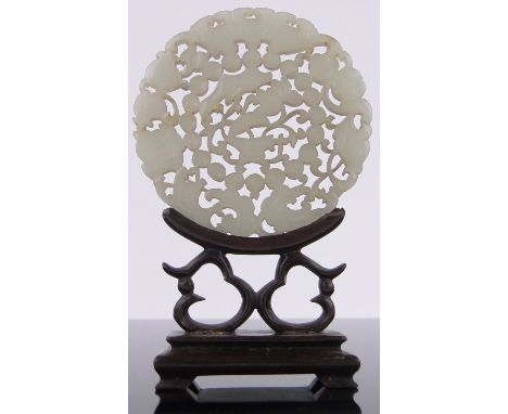 A Chinese relief carved and pierced jade disc,3" across, carved hardwood stand.