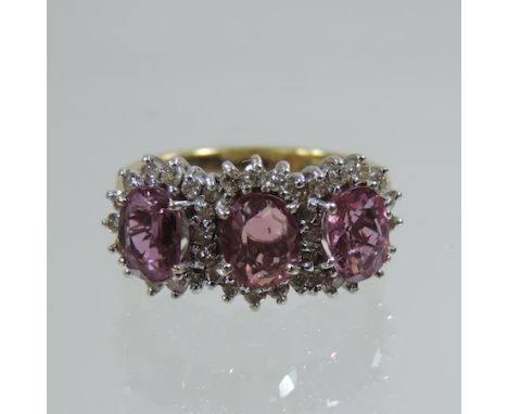 An 18 carat gold ruby and diamond triple cluster ring, boxed with valuation