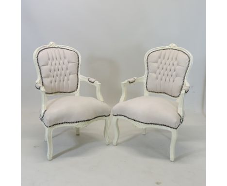 A pair of cream painted and upholstered button back open armchairs