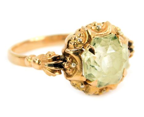 An Edwardian dress ring, set with octagonal cut and faceted pale green paste stone, in four claw setting, with ball and scrol