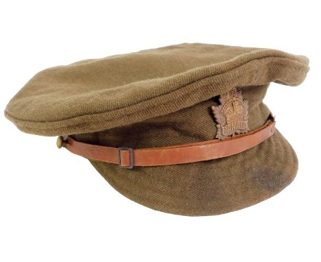 A WWI Canadian army peak cap, dated 1916, with leather adjusting belt and Canada cap badge, 22cm diameter.