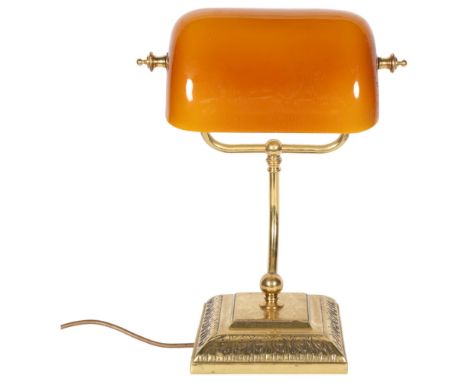 A brass desk lamp with amber glass swivel shade