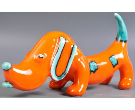 A retro vintage 1960's studio art pottery ceramic figurine figure of a sausage dog dachshund. Vibrant orange ground with pain