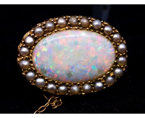 An opal and seed pearl brooch in gold, comprising an oval opal to the centre, approx 18 x 11mm, green, red, blue and orange p